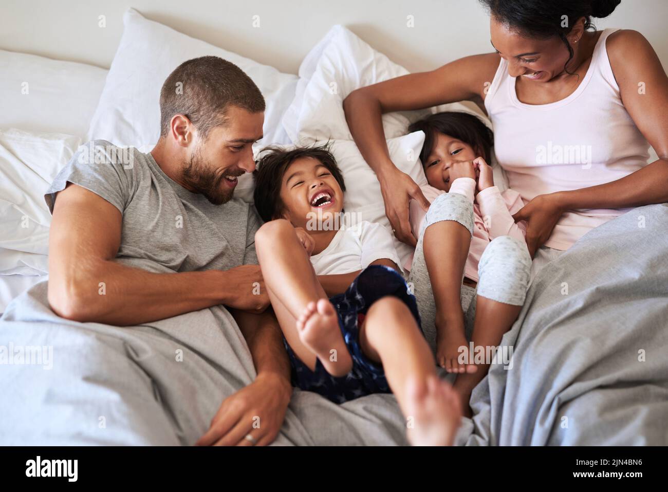 Familie ist alles über Liebe und Glück. Eine schöne junge Familie von vier Bonding und verbringen Zeit zusammen im Bett zu Hause. Stockfoto