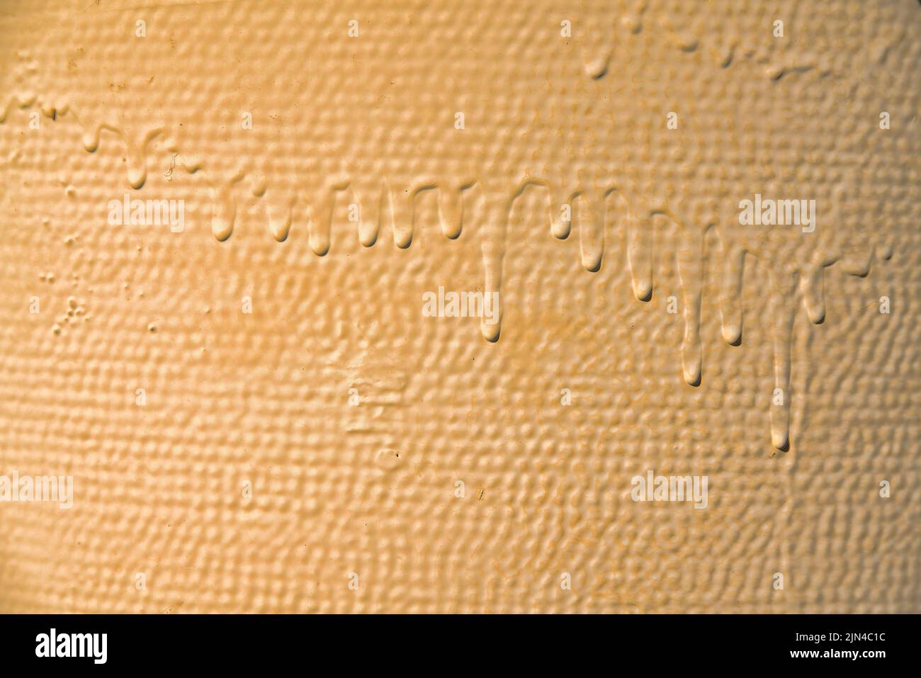 Nahaufnahme einer getrockneten gelblichen Farbe tropft - Tucson, Arizona. Getrocknete Farbe tropft in einer Reihe dicht auf einem rauen Oberflächenhintergrund ab. Stockfoto
