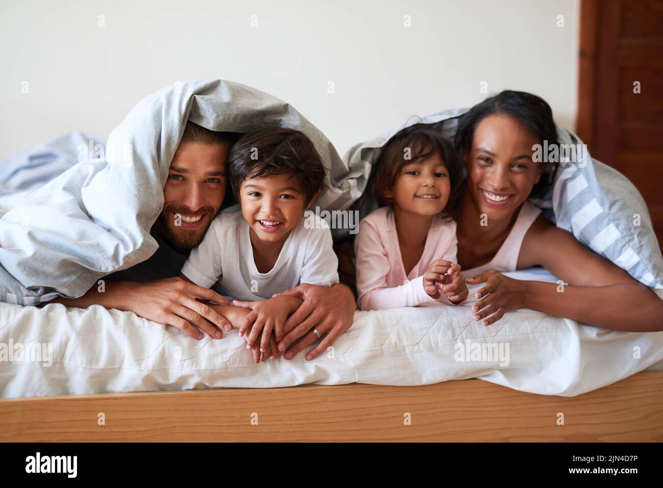 Waren heute nicht mehr aus dem Bett. Porträt einer schönen jungen vierköpfigen Familie, die sich zu Hause im Bett verbindet und Zeit miteinander verbringt. Stockfoto