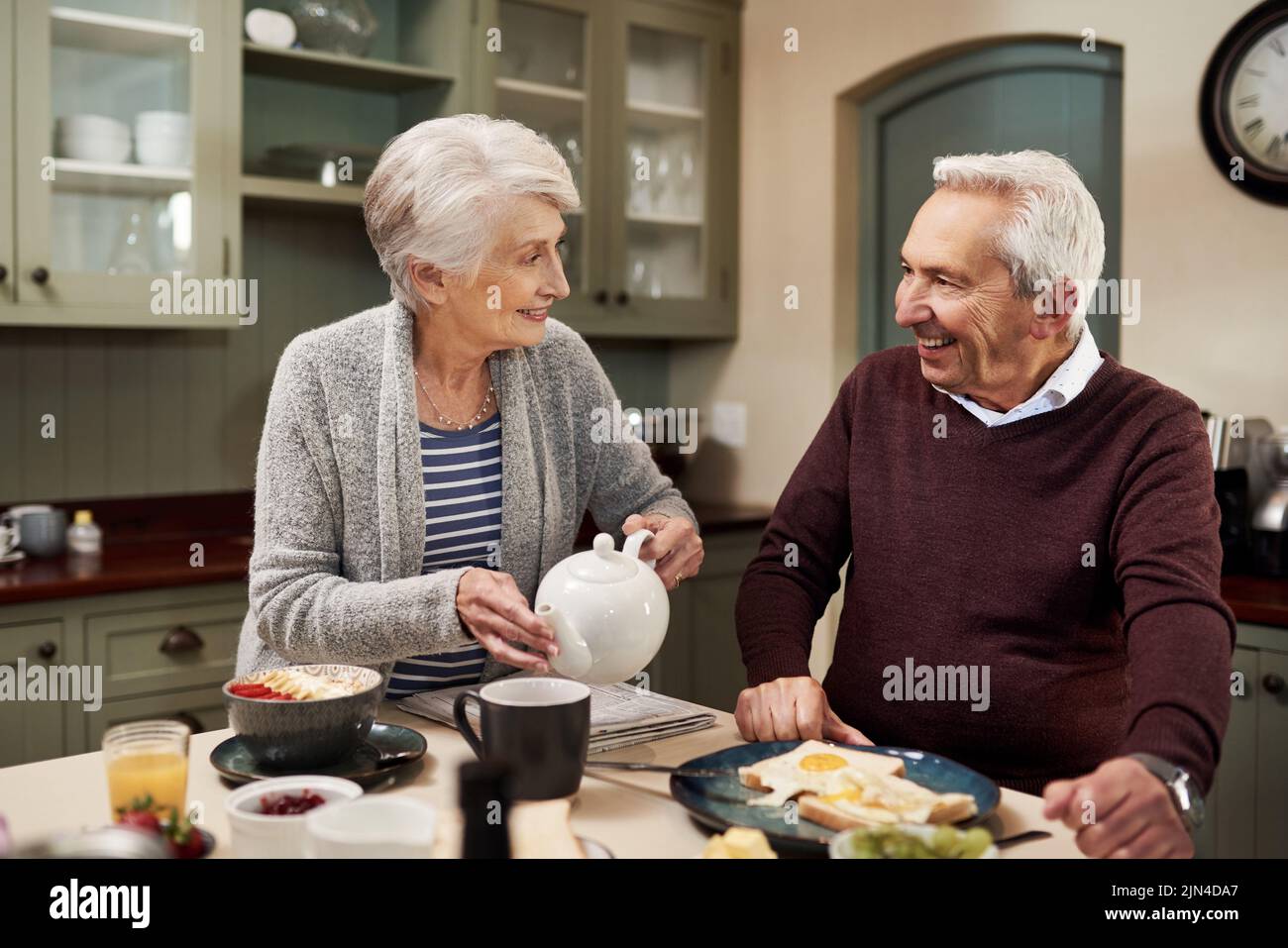 Du bist mein Lieblingstee. Ein liebevolles Seniorenpaar trinkt Tee und iß zusammen in der Küche zu Hause. Stockfoto