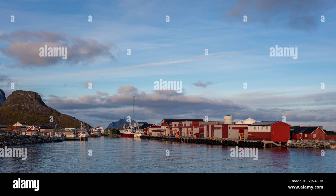 Der Blick auf farbenfrohe Gebäude und Boote am See unter dem blau bewölkten Himmel im Dorf Lofoten Stockfoto