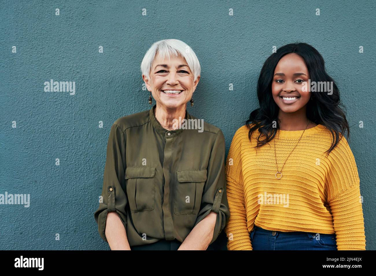 Wurden für den Erfolg zusammen gestellt. Porträt einer fröhlichen reifen und jungen Geschäftsfrau, die sich im Freien an einer Wand posiert. Stockfoto