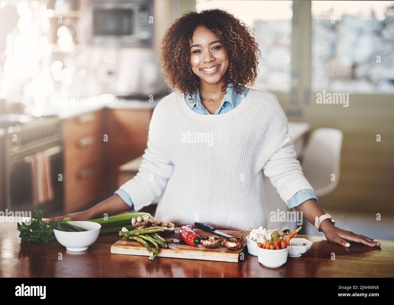 Glückliche Frau Kochen gesunde Lebensmittel aus der Ernährung Mahlzeit Plan auf heimischen Küchentisch für Wellness-Lifestyle. Schöne, selbstbewusste Frau, lächelnd beim Making Stockfoto