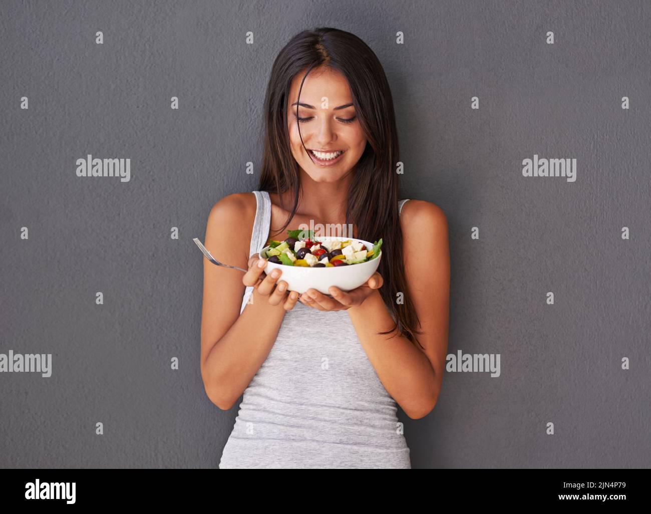 Gesunde junge Frau essen ihre frische Lebensmittel Salatschüssel. Lächelnd schöne Frau hält und genießt es, ihre saubere grüne Diät Gericht von Gemüse zu essen Stockfoto