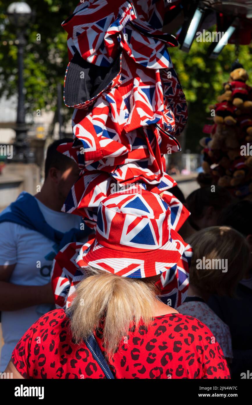 Eine Frau, die einen Sonnenhut mit der Flagge von Union Jack aus einem Souvenirladen in Westminster, London, Großbritannien, ausprobiert. Patriotischer Schutzhut Stockfoto