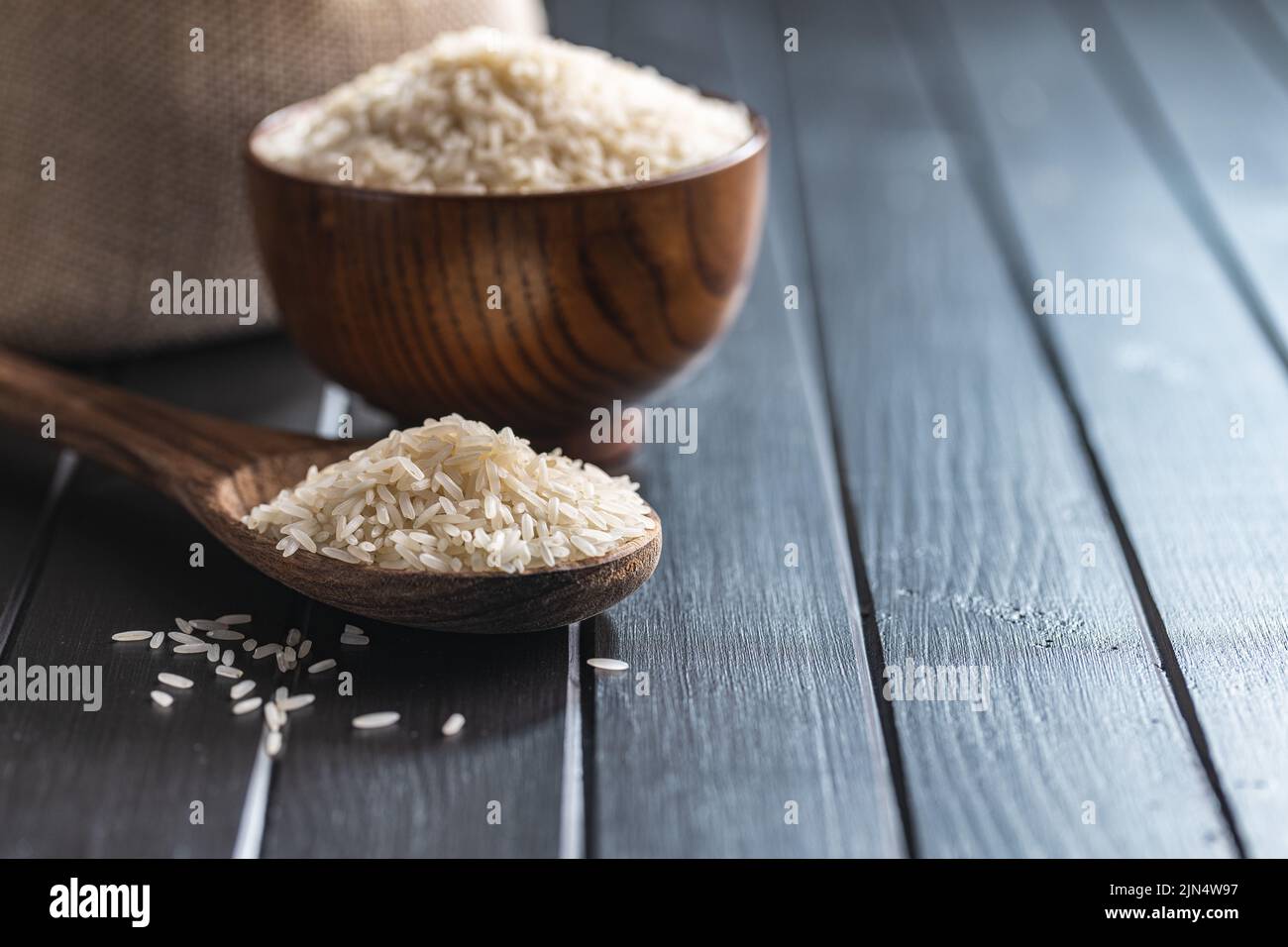 Ungekochten weißen Reis auf einem Holzlöffel auf schwarzem Tisch. Stockfoto