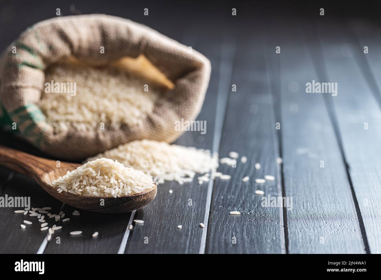 Ungekochten weißen Reis auf einem Holzlöffel auf schwarzem Tisch. Stockfoto