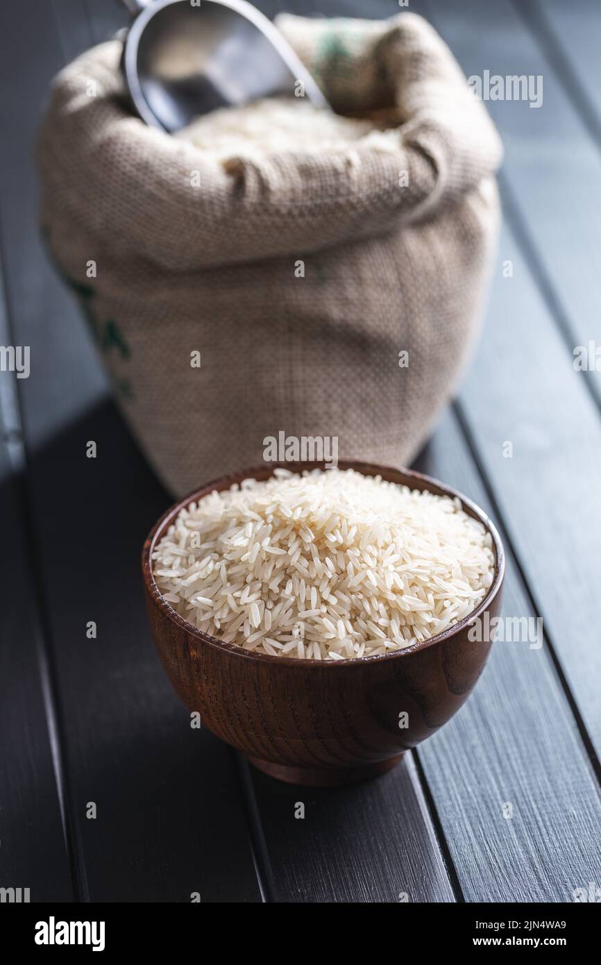 Ungekochten weißen Reis in einer Holzschüssel auf schwarzem Tisch. Stockfoto