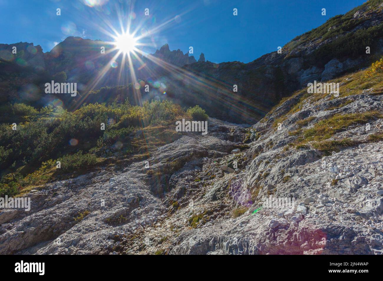 Sonnenstrahlen filtern zwischen den Dolomitengipfeln über dem Wasserfall in der Comelico Region Stockfoto