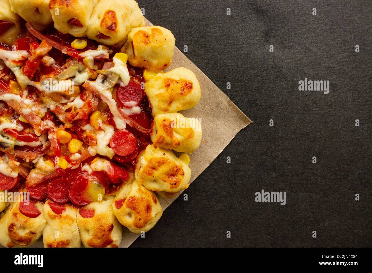 Leckere Pizza mit Pilzauflage, Mais, Hühnerwurst, Speck, Mayonnaise, Grillsauce, Tomate, Chili auf schwarzem Hintergrund. Stockfoto