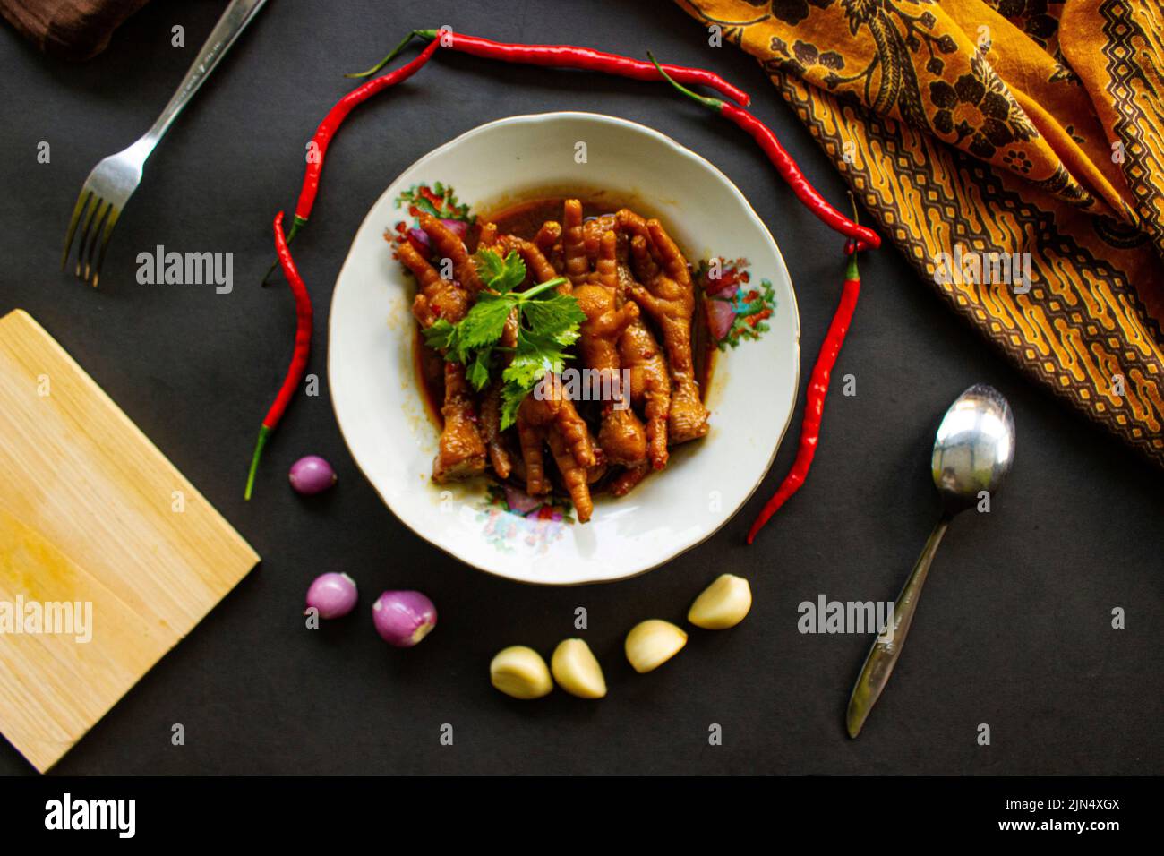Würzige Hähnchenfüße mit Sellerie, Chili, Zwiebel, Knoblauch, serviert mit einem weißen Teller auf dem Tisch Stockfoto