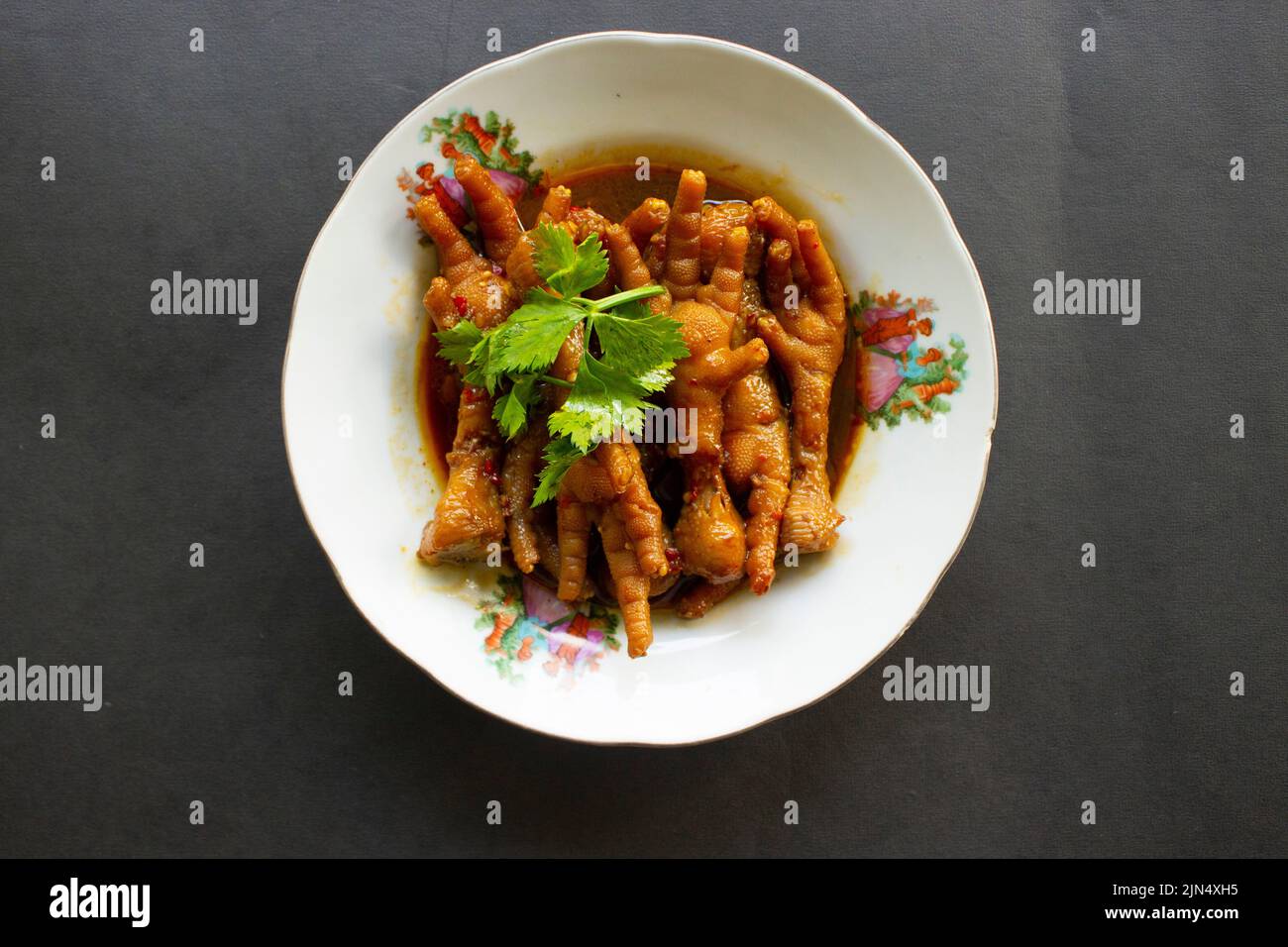 Würzige Hähnchenfüße mit Sellerie, Chili, Zwiebel, Knoblauch, serviert mit einem weißen Teller auf dem Tisch Stockfoto