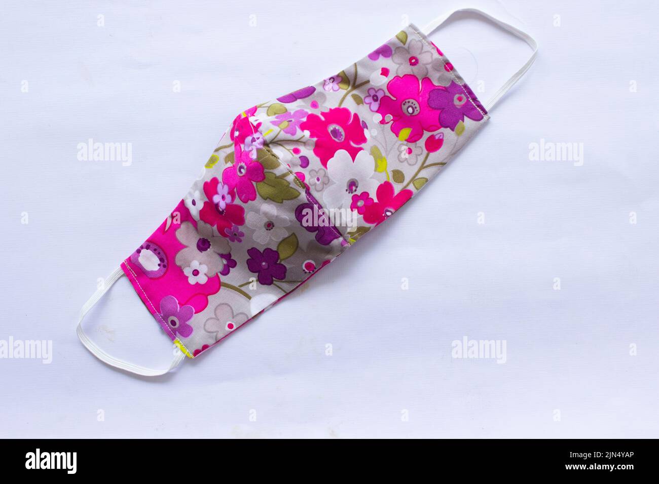 Stoff Maske oder Stoff Gesichtsmaske mit Baumwollstoff Blumenmuster handgefertigten Kunsthandwerk isoliert auf weißem Hintergrund. Diese hygienische Maske für Deckelmund und Stockfoto