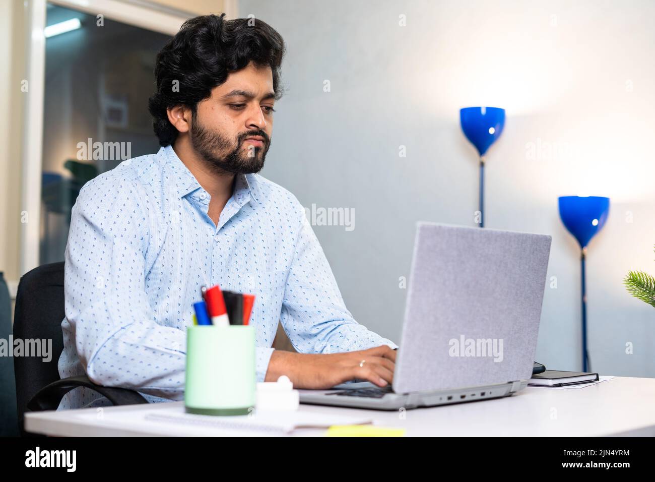 Junge Firmenangestellte oder Unternehmer ernsthaft auf Laptop arbeiten, während im Büro sitzen - Konzept der Beschäftigung, hart arbeiten Lebensstile und Stockfoto