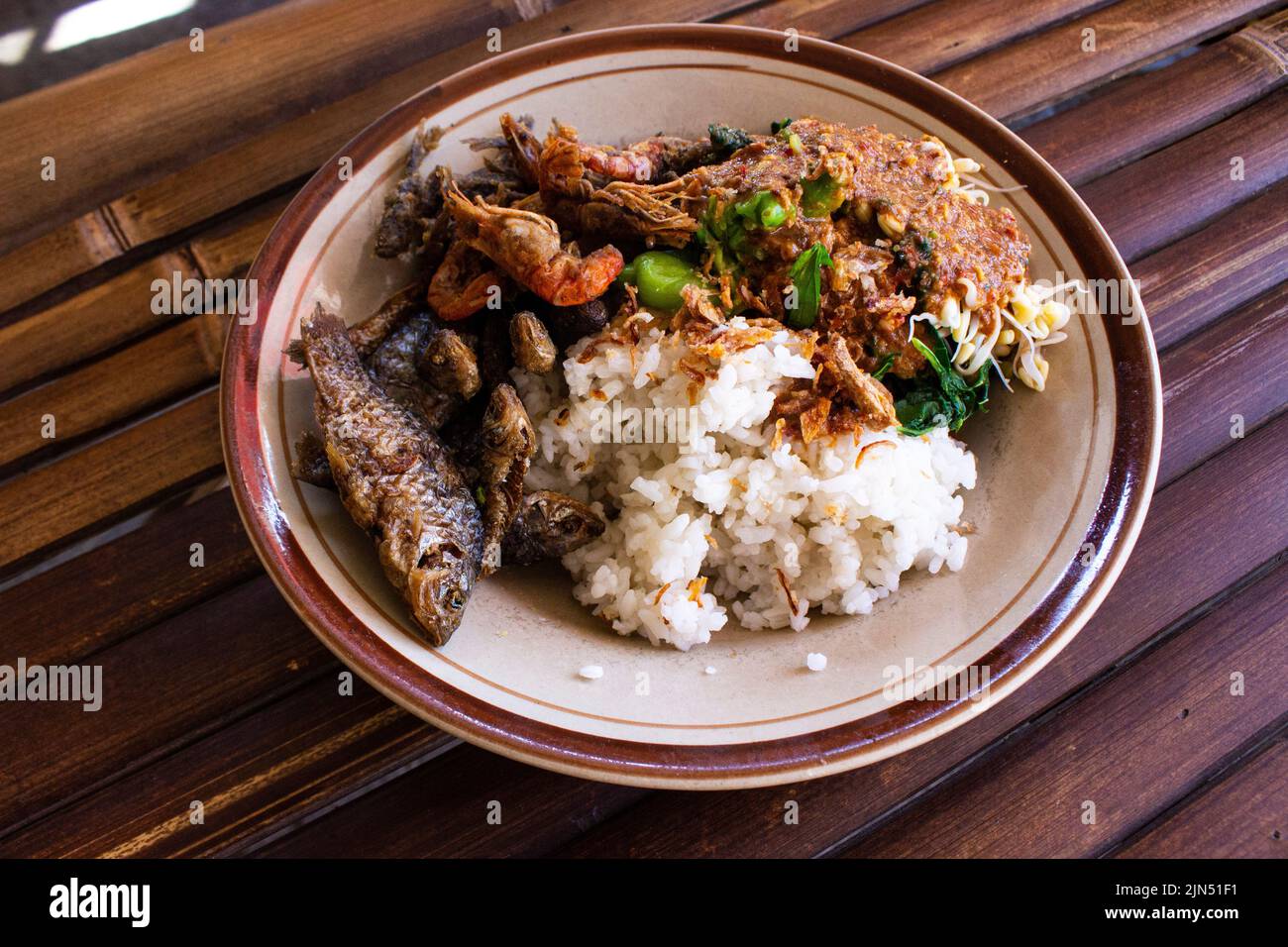 Nasi Pecel oder sego Pecel ist ein traditionelles javanesisches Reisgericht aus gedünstetem Reis mit Gemüsesalat, Erdnusssauce, Tempeh, Tofu-Bohnensprossen und Crackern Stockfoto