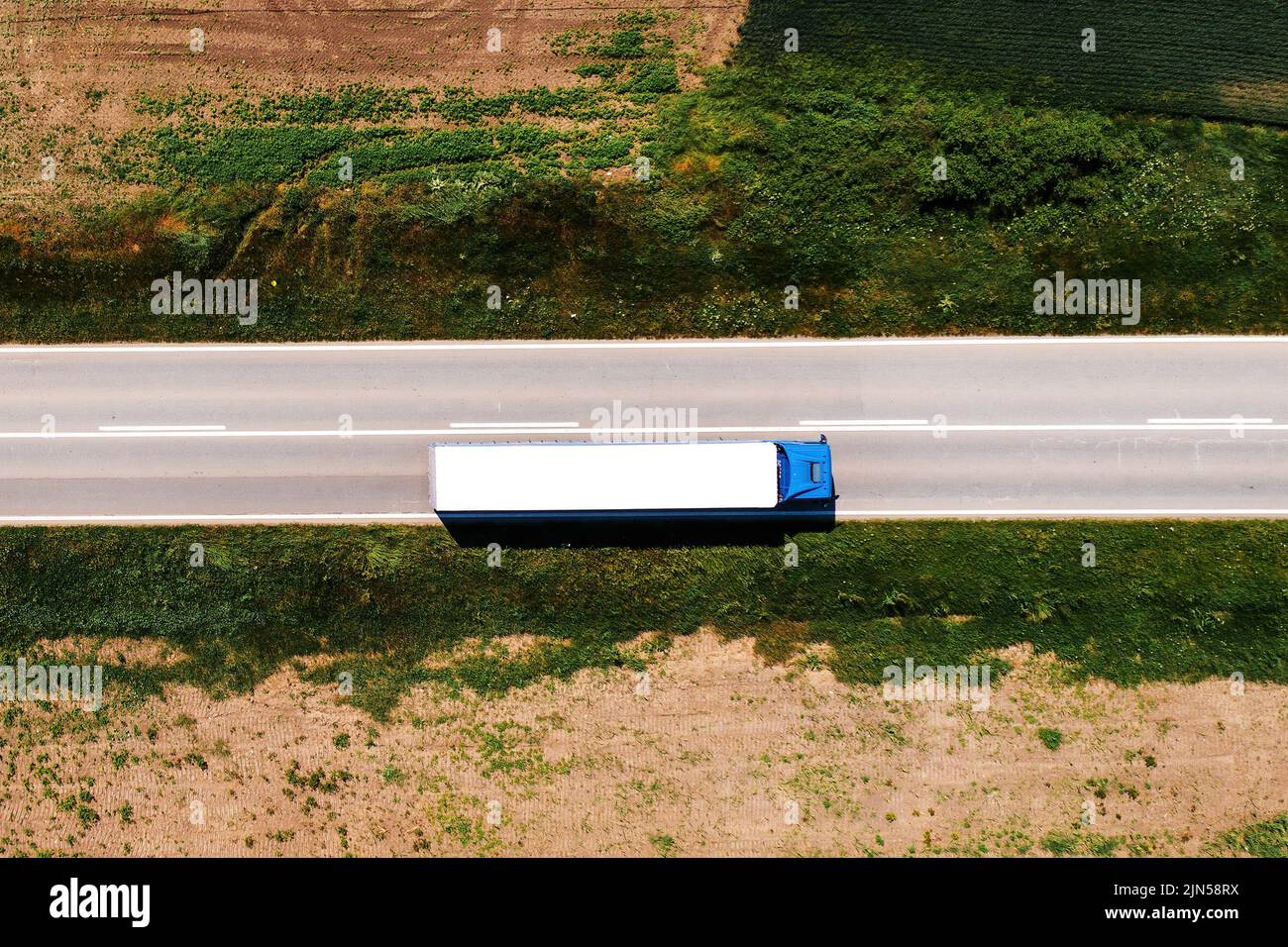 Luftaufnahme von Sattelschlepper, die entlang der Autobahn durch die Landschaft fahren, Drohne pov direkt oben am sonnigen Frühlingstag. Transport und lo Stockfoto