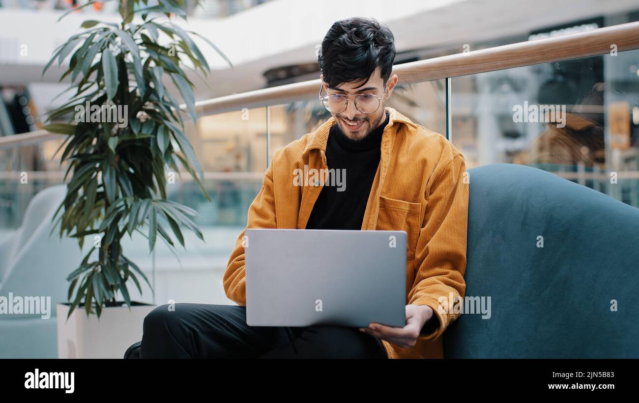 Junge seriöse arabische männliche Freiberufler in Brille sitzt Blick auf Laptop-Bildschirm funktioniert aus der Ferne geladen in Gedanken über die Arbeit denkt über Geschäftsproblem Stockfoto
