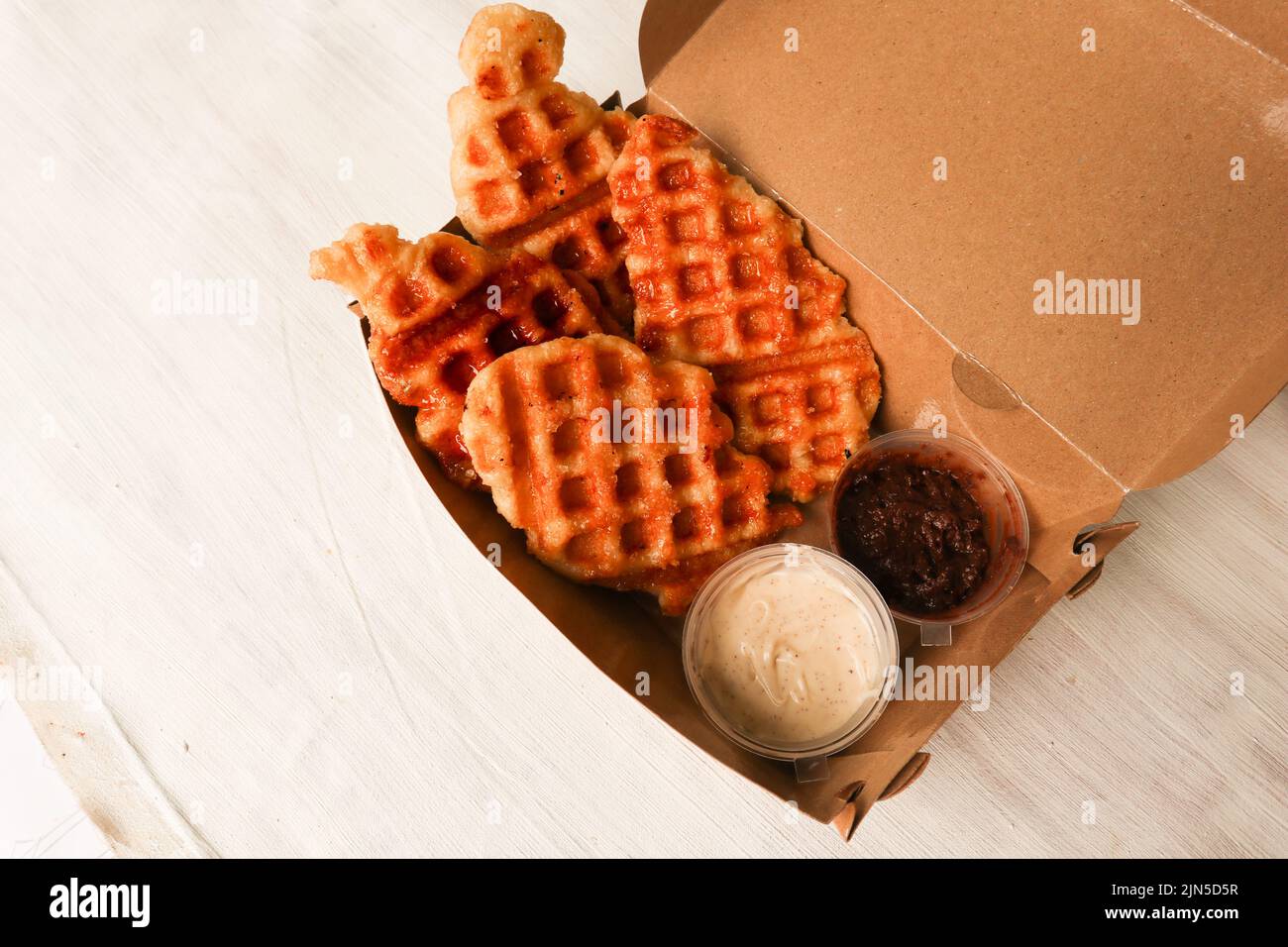 Croissant Waffel oder Croffle mit Schokoladensauce serviert in Box und weißem Hintergrund Stockfoto