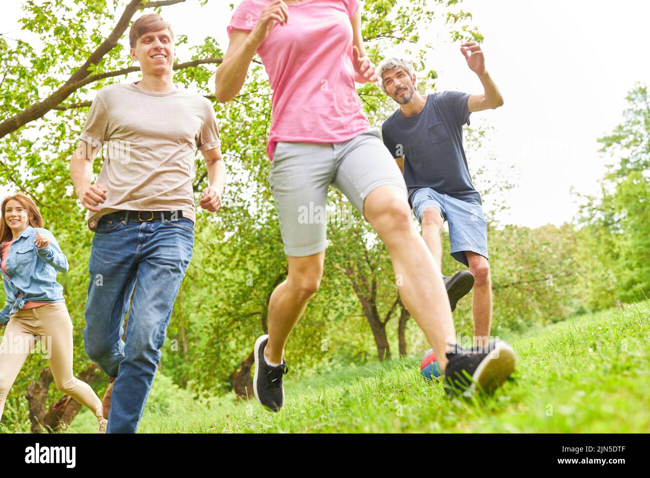 Eine Gruppe junger Menschen, die im Sommer als Fitnesstraining oder Spiel auf einer Wiese laufen Stockfoto