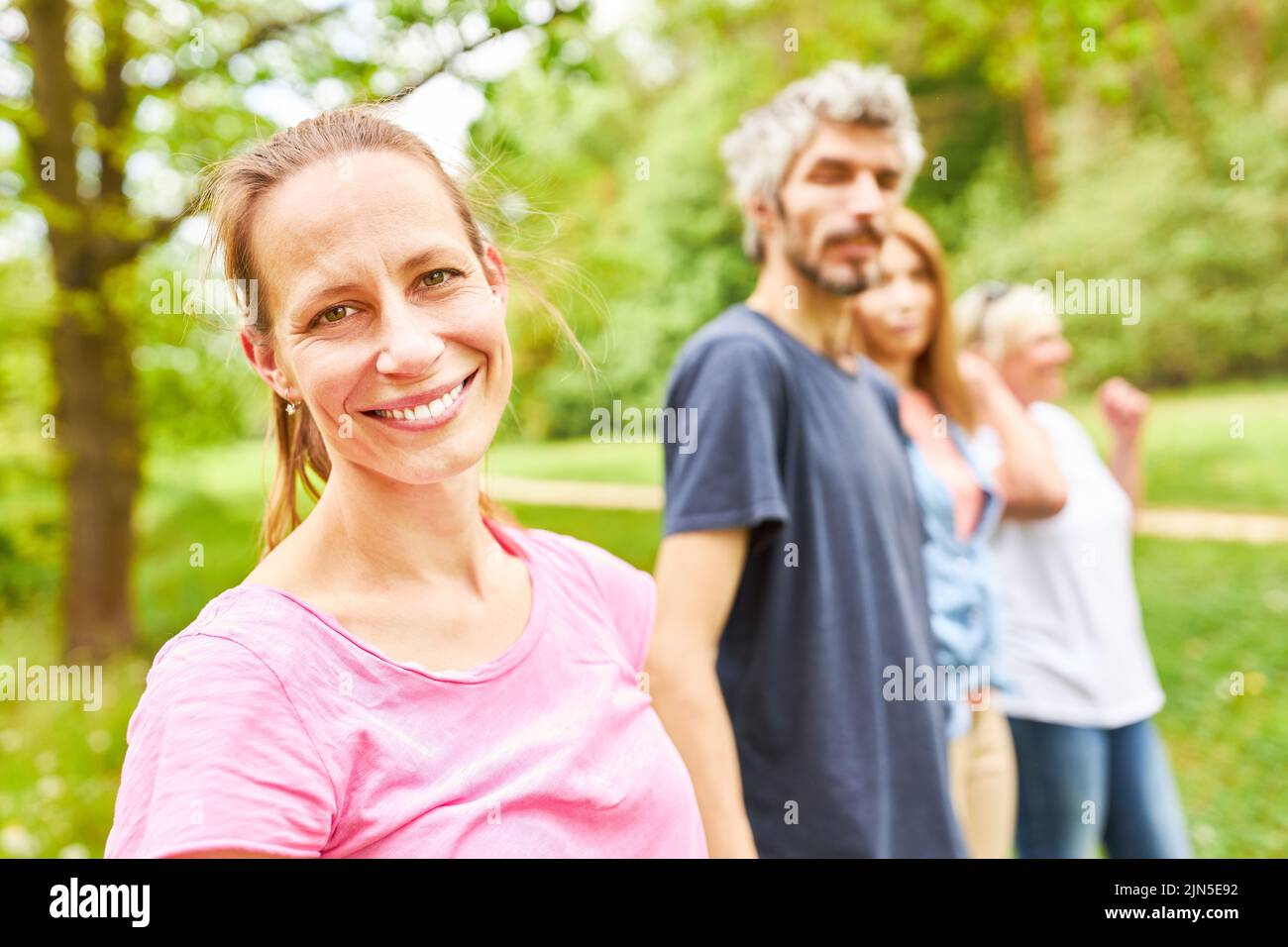 Lächelnde junge Frau und ihre Freunde oder Familie machen einen Ausflug in die Natur Stockfoto