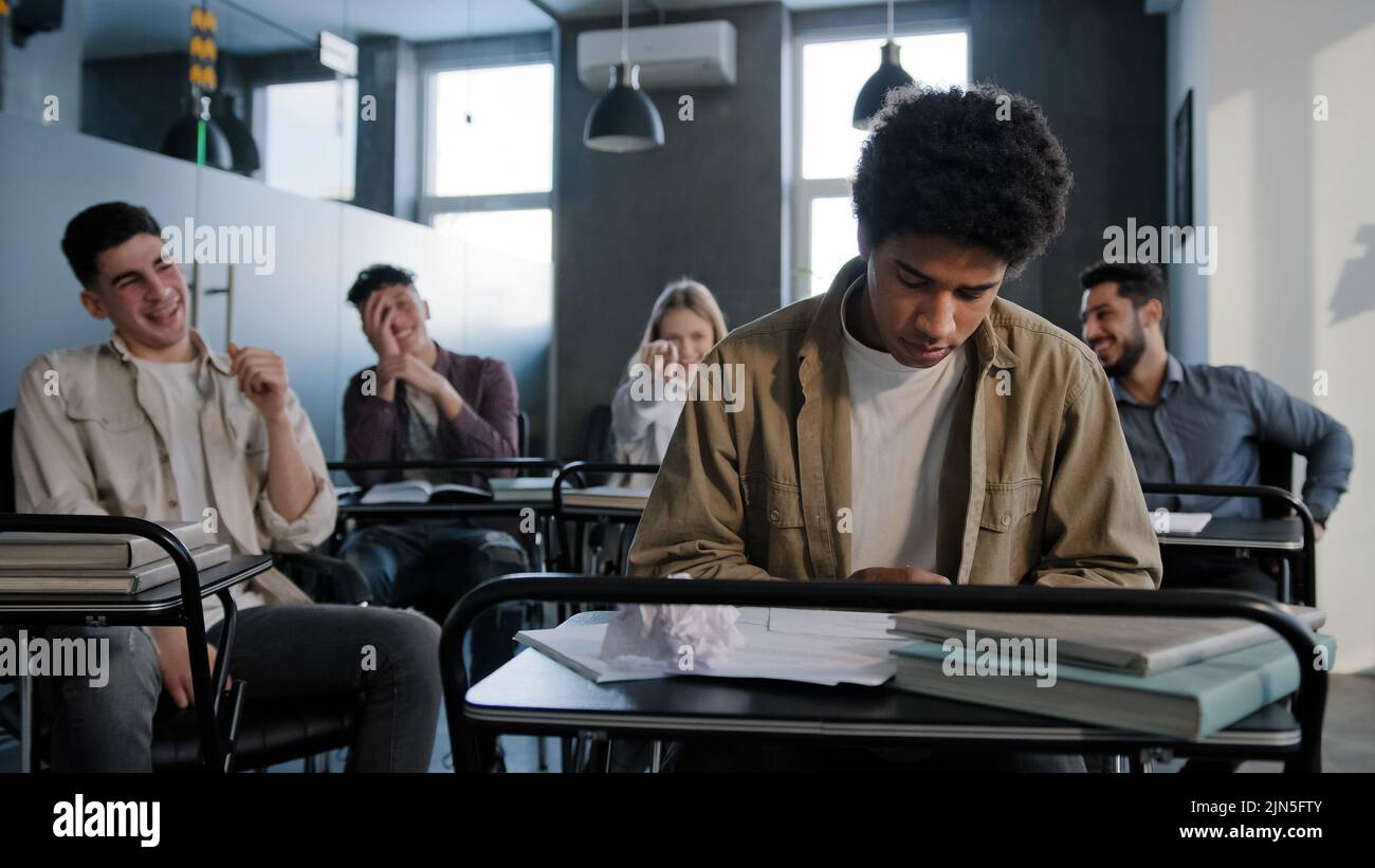 Unglücklicher afroamerikanischer Student Verlierer Gefühl spöttisch Mobbing Wut von Klassenkameraden leiden unter Missbrauch junge aufgeregt beunruhigt Kerl sitzt allein in Stockfoto