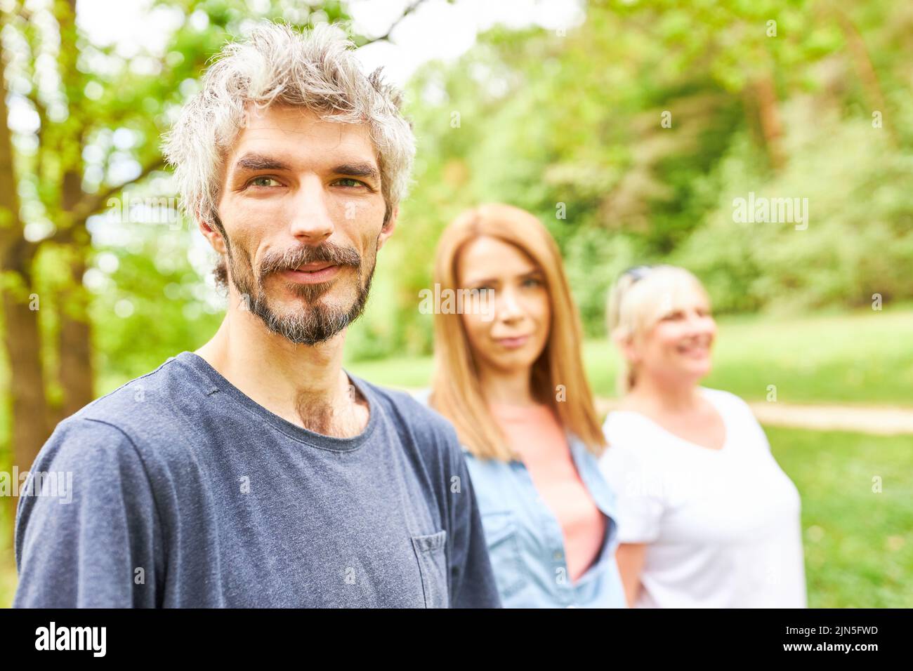 Junger Mann und Freunde oder Familie in der Natur im Park auf einer Reise im Sommer Stockfoto