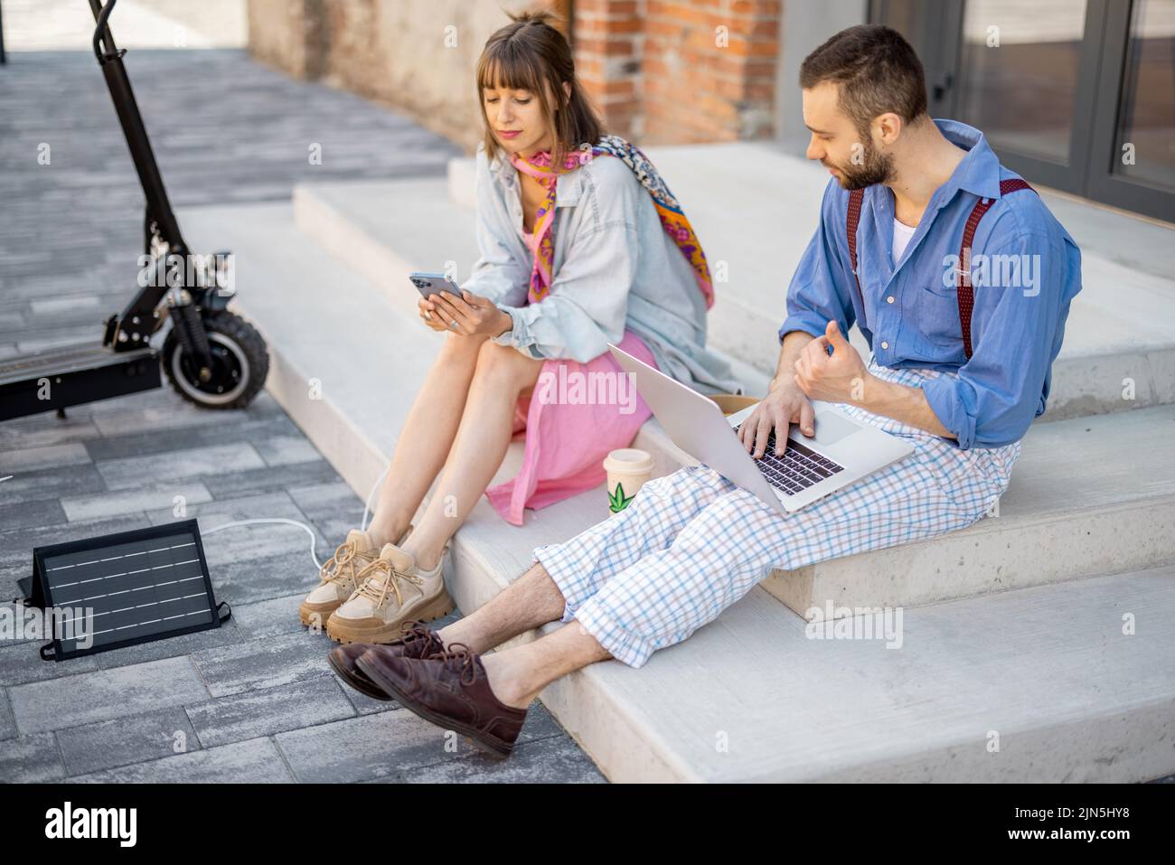 Elegante Kollegen arbeiten im Freien am Telefon und Laptop Stockfoto