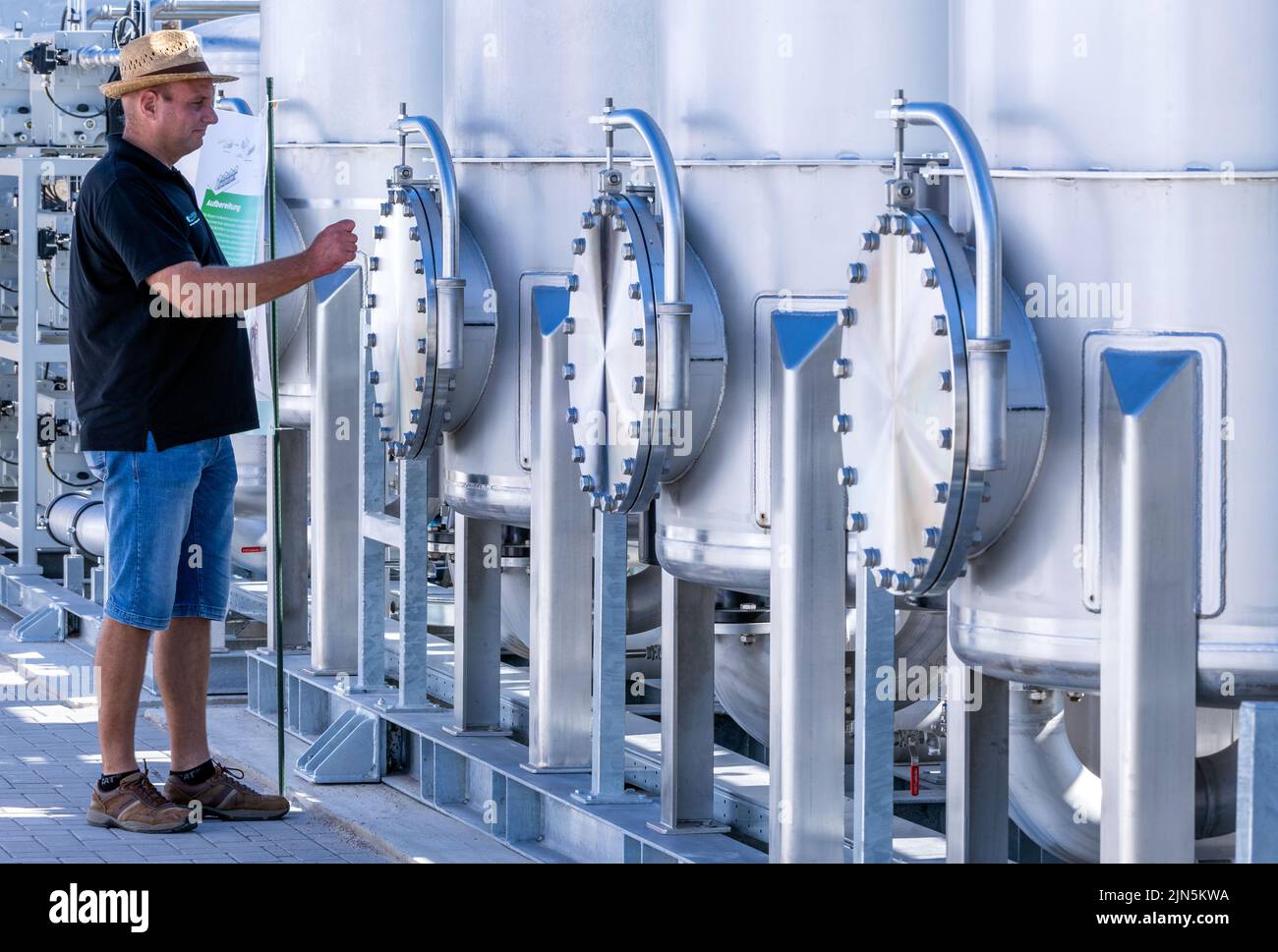 Darchau, Deutschland. 09. August 2022. Ein Landwirt inspiziert, was der Hersteller als erste kompakte Bio-LNG-Anlage auf dem Gelände der Agrarvereinigung Darchau angibt. In Zukunft wird das Werk in der Lage sein, grünen Kraftstoff aus der heimischen Produktion für den schweren Lkw- und Busverkehr zu liefern. Die Anlage soll jährlich etwa 1,3 Millionen Liter fossilen Diesel ersetzen und bis zu 7.000 Tonnen CO2 einsparen. Quelle: Jens Büttner/dpa/Alamy Live News Stockfoto