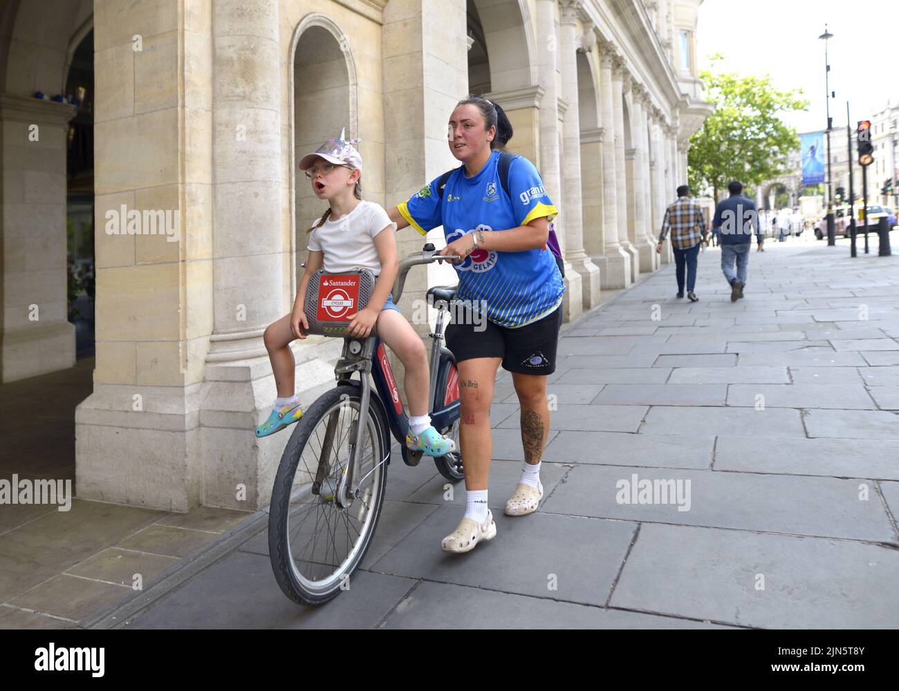 London, England, Großbritannien. Junges Mädchen mit einem Einhorn Hut auf einem Boris Bike in the Strand Stockfoto