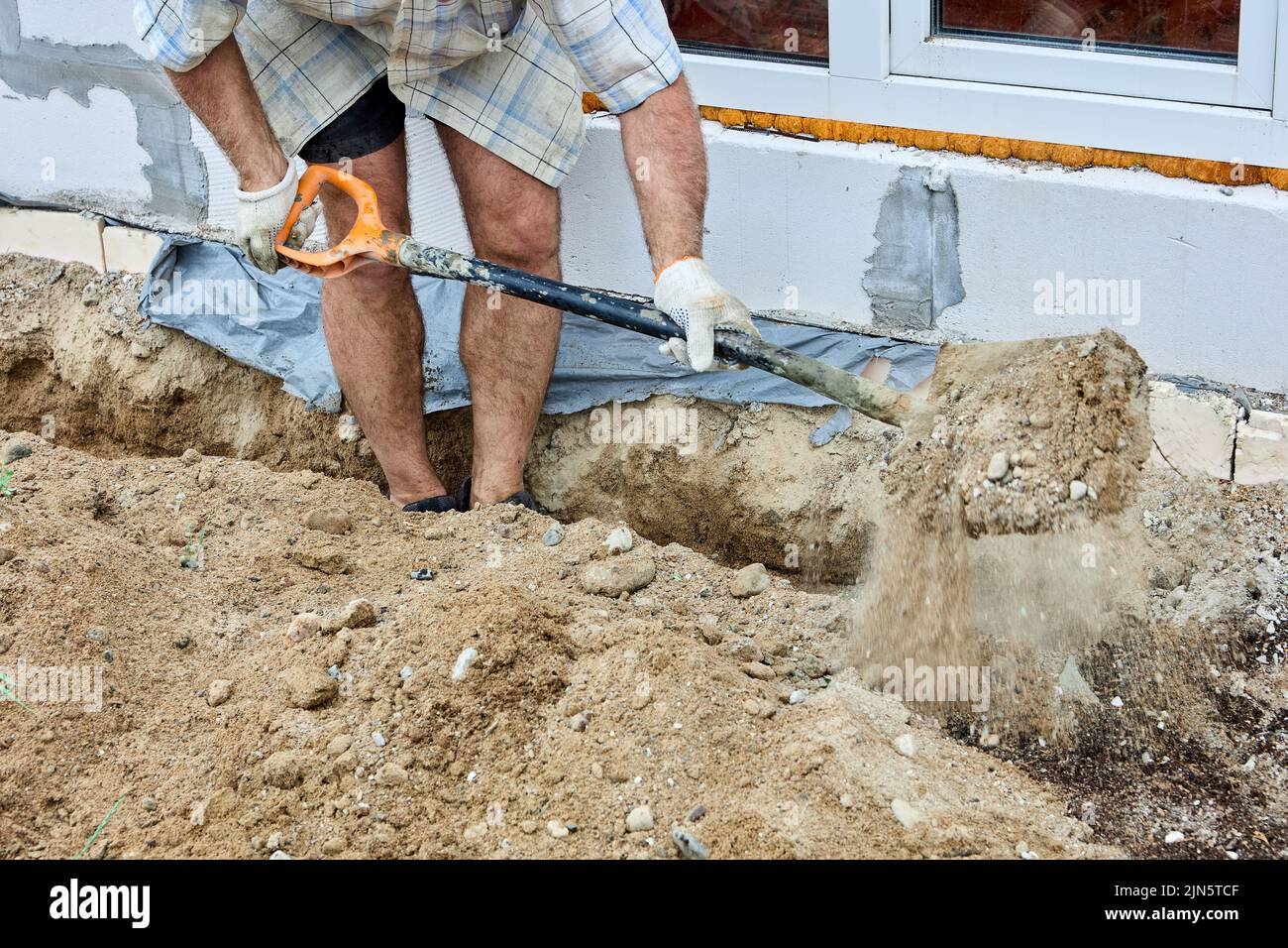 Graben Graben für die Verlegung Kabel, Bauarbeiter nutzt Schaufel, um Boden zu nehmen. Stockfoto