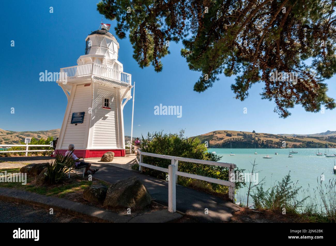 Ein paar Radfahrer und ihre geparkten Fahrräder am Akaroa Head Lighthouse mit Blick auf Akaroa Bay, einer ehemaligen französischen Siedlung in der Kleinstadt von Stockfoto