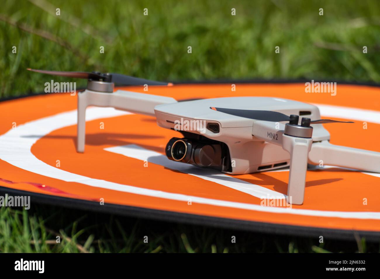 Kharkiv, Ukraine - 22. April 2021: DJI Mavic Mini 2 Drohne mit cpl Linsenfilter auf orangefarbener Landeplattform. Quadcopter auf klappbarer Trägerrakete aus Nylon Stockfoto Kharkiv, Ukraine - 22. April 2021: DJI Mavic Mini 2 Drohne mit cpl Linsenfilter auf orangefarbener Landeplattform. Quadcopter auf klappbarer Trägerrakete aus Nylon Stockfoto