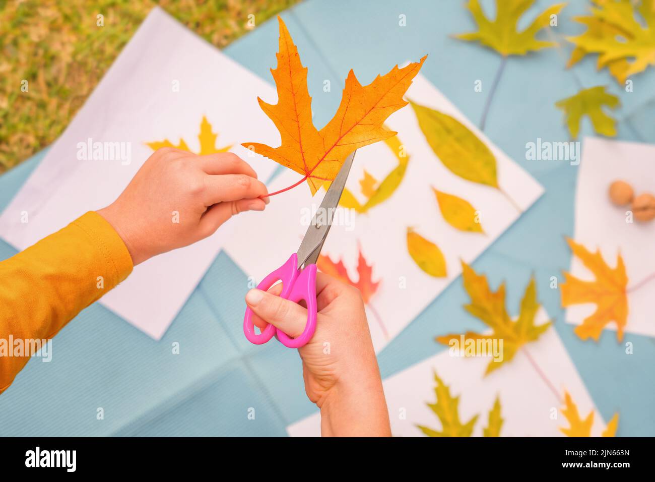 DIY Art Kind kreativ spielen lernen außerhalb der Schule Outdoor Learning Park. Kinder Workshop Kinder Schere Schneiden Blätter Kunst Handwerk Kinder handgefertigten Herbst Stockfoto