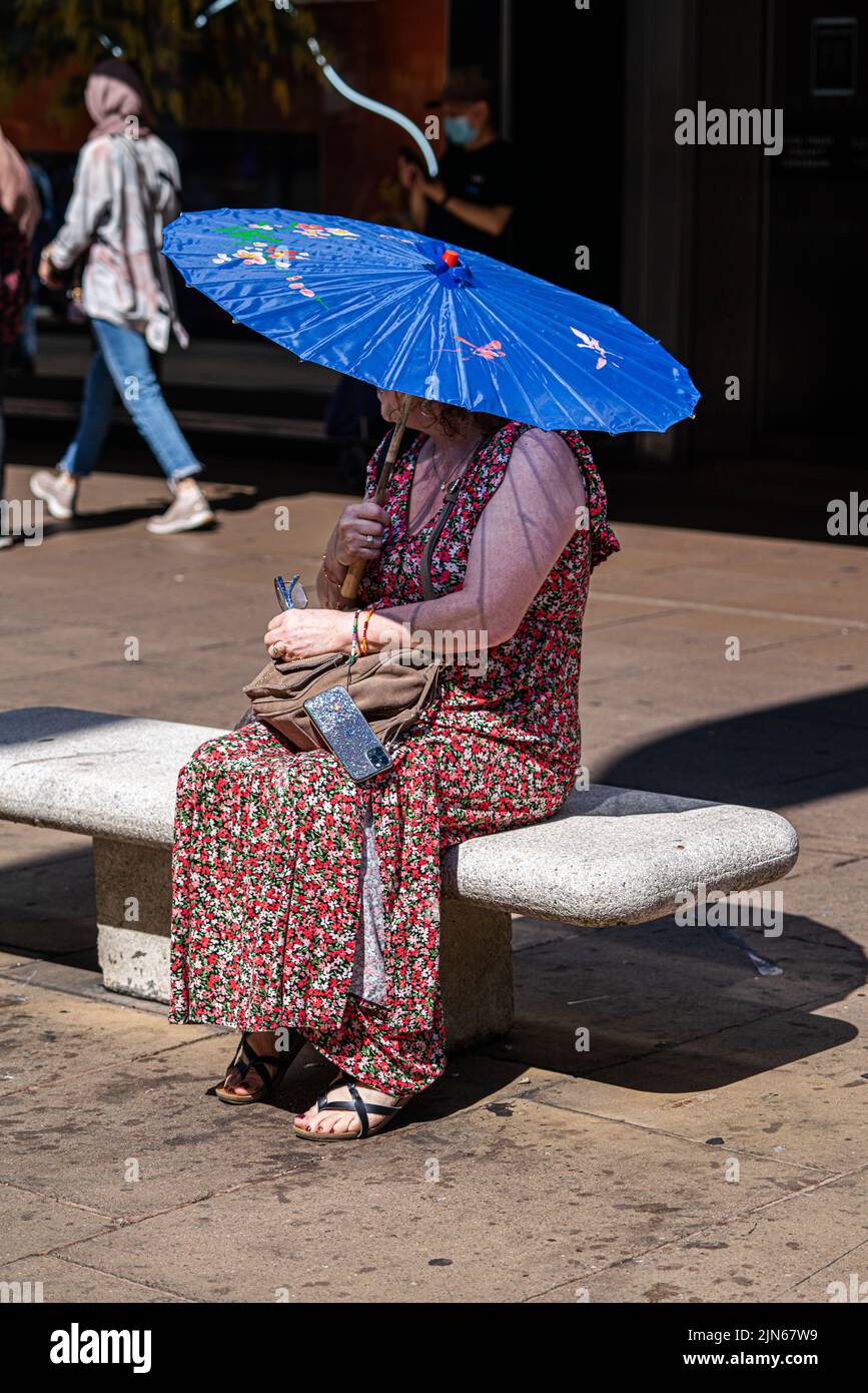 London, Großbritannien. 9. August 2022 Eine Frau hält einen Sonnenschirm, um sich vor der Hitze in der Oxford Street zu schützen. Die britische Gesundheitsbehörde hat eine Warnung ausgegeben, da England auf einem Niveau von 3 Gesundheitswarnungen gesetzt wird, die voraussichtlich in der nächsten Woche auf Mitte 30 Grad celsius steigen werden. Kredit. amer Ghazzal/Alamy Live Nachrichten Stockfoto