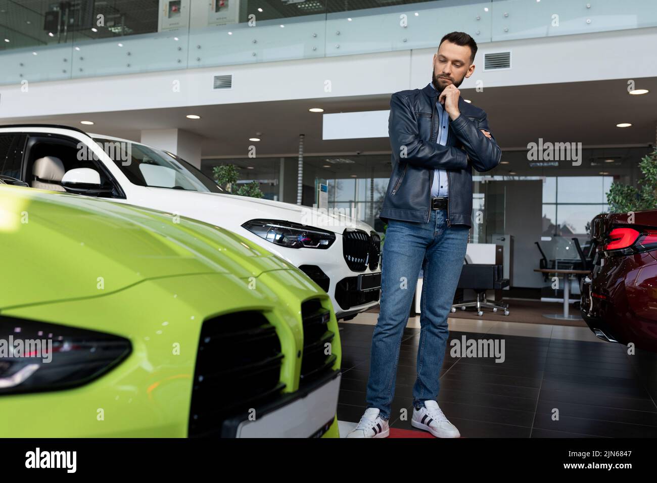 Ein junger Mann wählt sich in einem Autohaus einen Sportwagen aus Stockfoto
