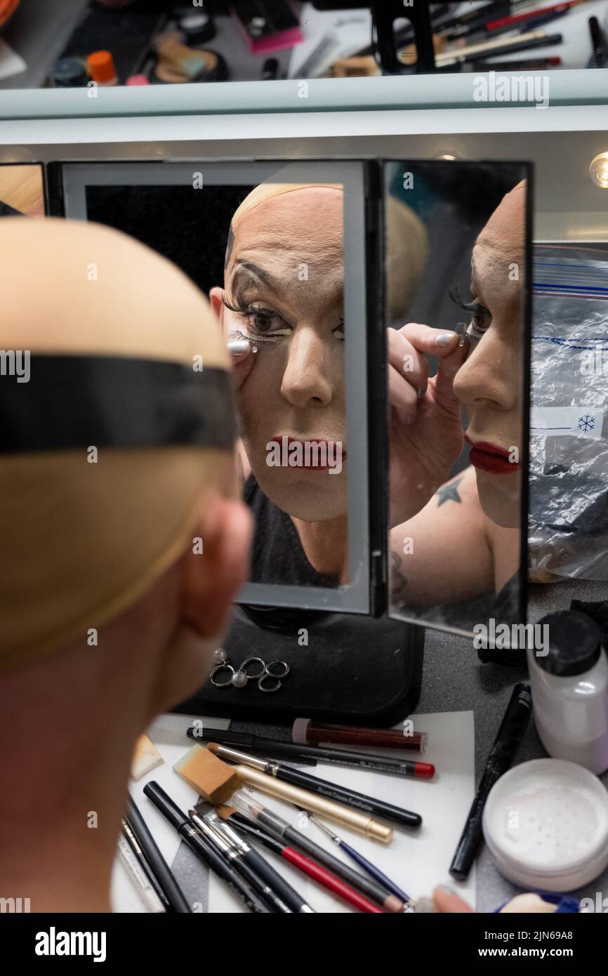 Nicht-binäre Person Anwendung Drag Queen Make-up Backstage, Blick in Spiegel Stockfoto