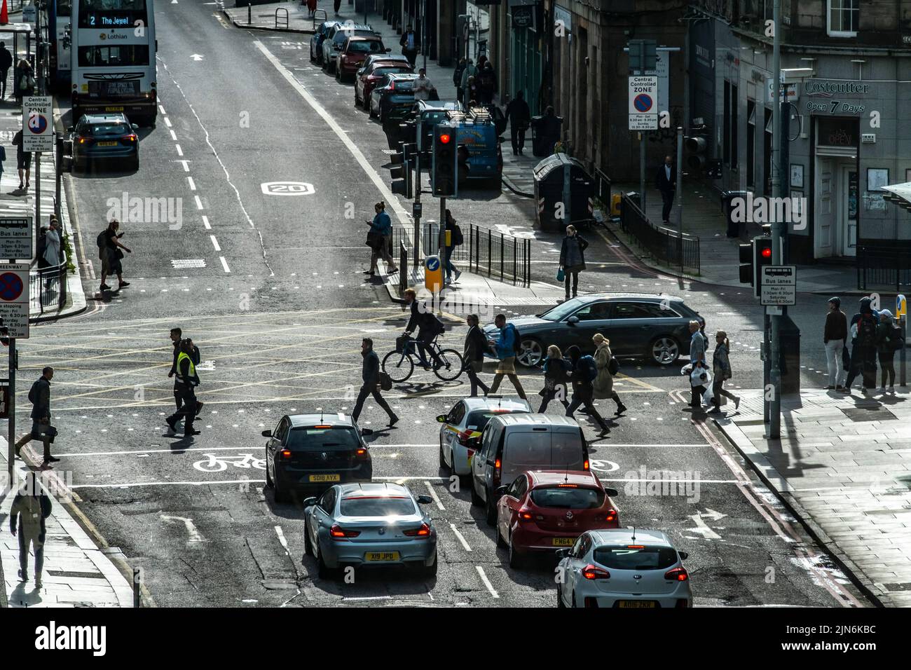 Fußgänger und Radfahrer in Silhouette, die die geschäftige Straße in Edinburgh überqueren Stockfoto
