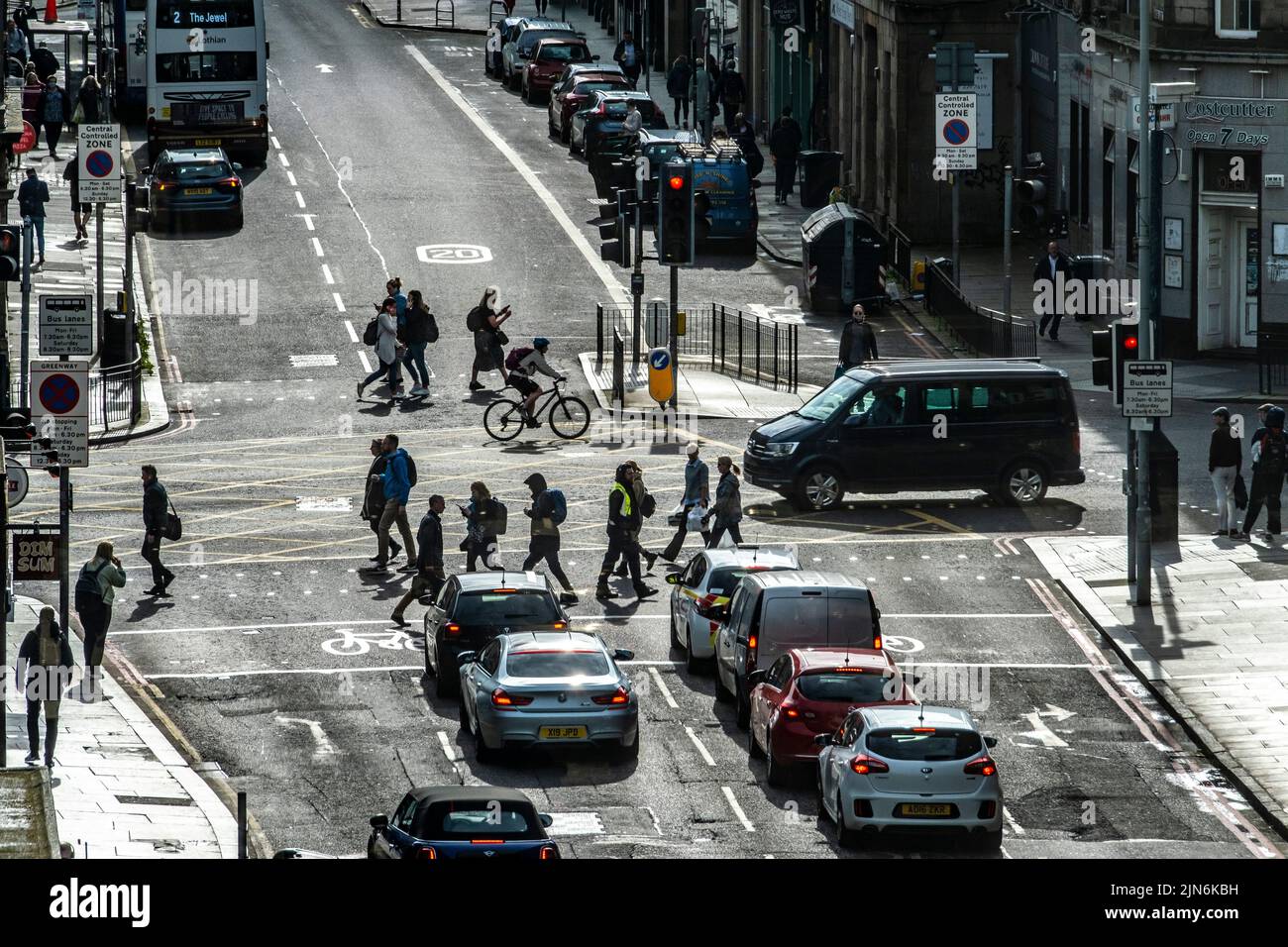 Fußgänger und Radfahrer in Silhouette, die die geschäftige Straße in Edinburgh überqueren Stockfoto