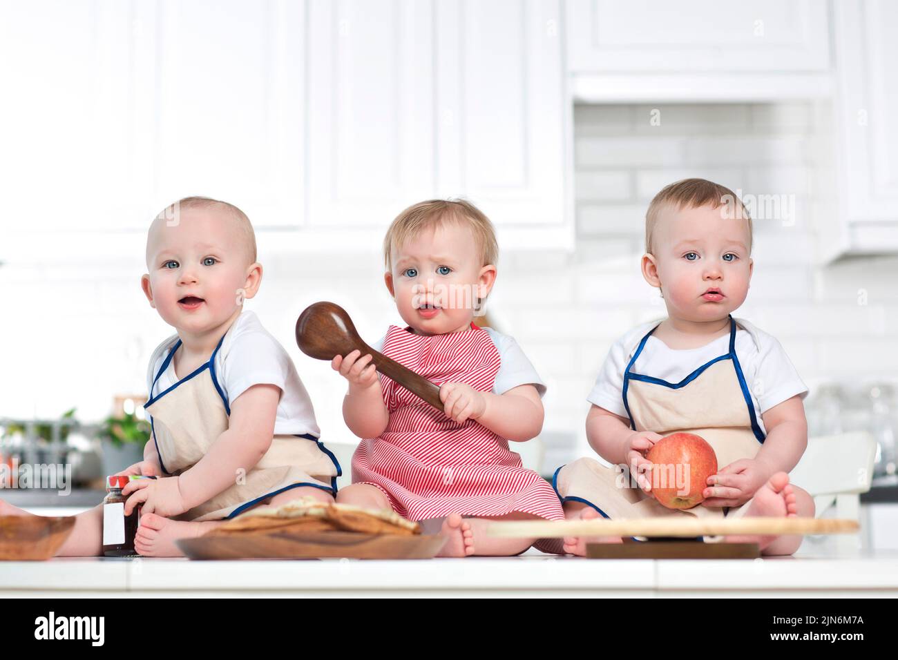 Drei Kleinkinder auf dem Küchentisch, Babynahrung Mockup Stockfoto