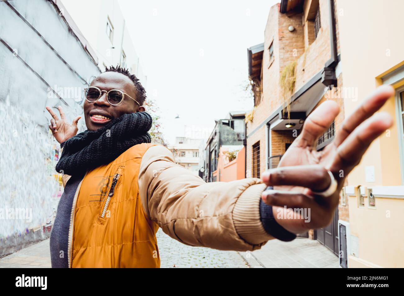 Junger afrikanischer Mann, der lächelnd die Kamera mit offenen Armen ansah Stockfoto