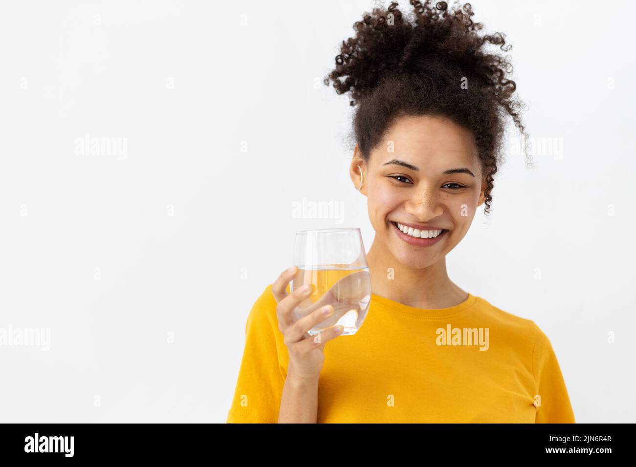 Gesunder Lebensstil lächelnde junge Frau, die ein Glas frisches sauberes Wasser hält und die Kamera anschaut und freundlich lächelt Stockfoto