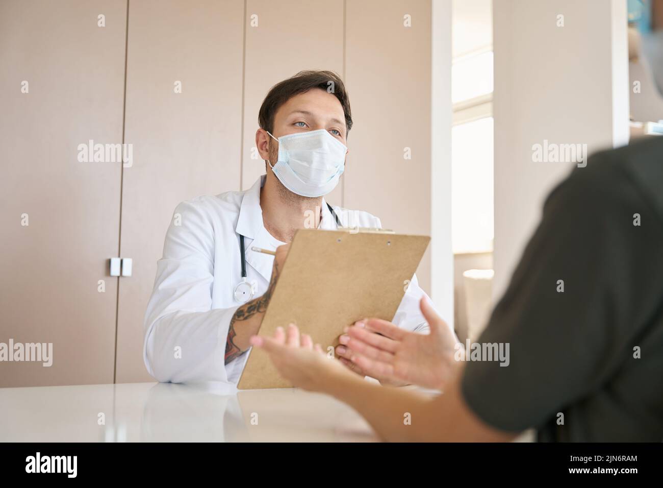 Der Arzt zeichnet die Beschwerden des Patienten schriftlich auf Stockfoto