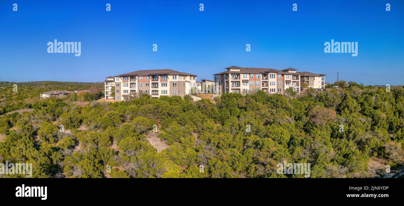 Austin, Texas – komplexe Apartmentgebäude in der Nähe der Klippe mit Panoramablick. Wohngebäude auf einem Hang mit Bäumen gegen den klaren Berg Stockfoto