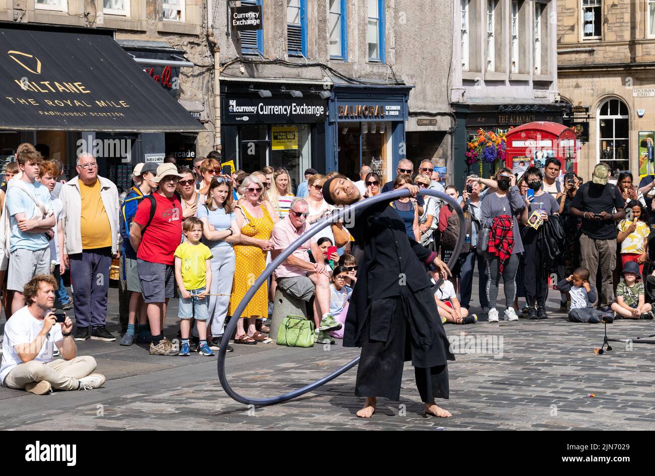 Royal Mile, Edinburgh, Schottland, Großbritannien, 9.. August 2022. Edinburgh Festival Straßenkünstler Fringe: Ein Mann spielt akrobatische Stunts auf einem cyr-Rad für die Menge im Sonnenschein Stockfoto