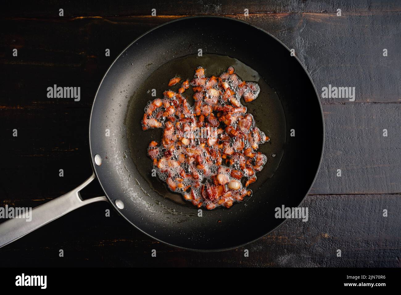 Gewürfelter Bacon in einer großen Pfanne dargestellt Angesehene von oben: Kleine Stücke Speck sizzling in einer antihaftbeschichteten Pfanne Stockfoto