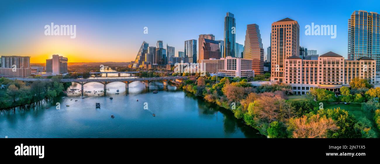 Austin, Texas – Panoramaansicht der Stadt und des Colorado River vor dem Sonnenuntergang. Es gibt Brücken über den Fluss mit Booten unter und einen Blick auf die Skys Stockfoto