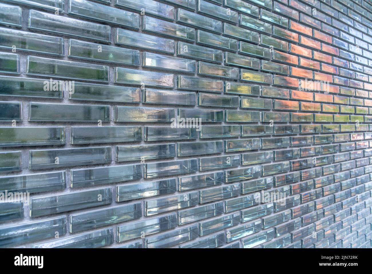 Reflektierende optische Backsteinwände aus Glas in Austin, Texas. Außenansicht eines Gebäudes mit Glasziegelwänden mit Reflexionen in einem verlaufenden Bindungsmuster. Stockfoto
