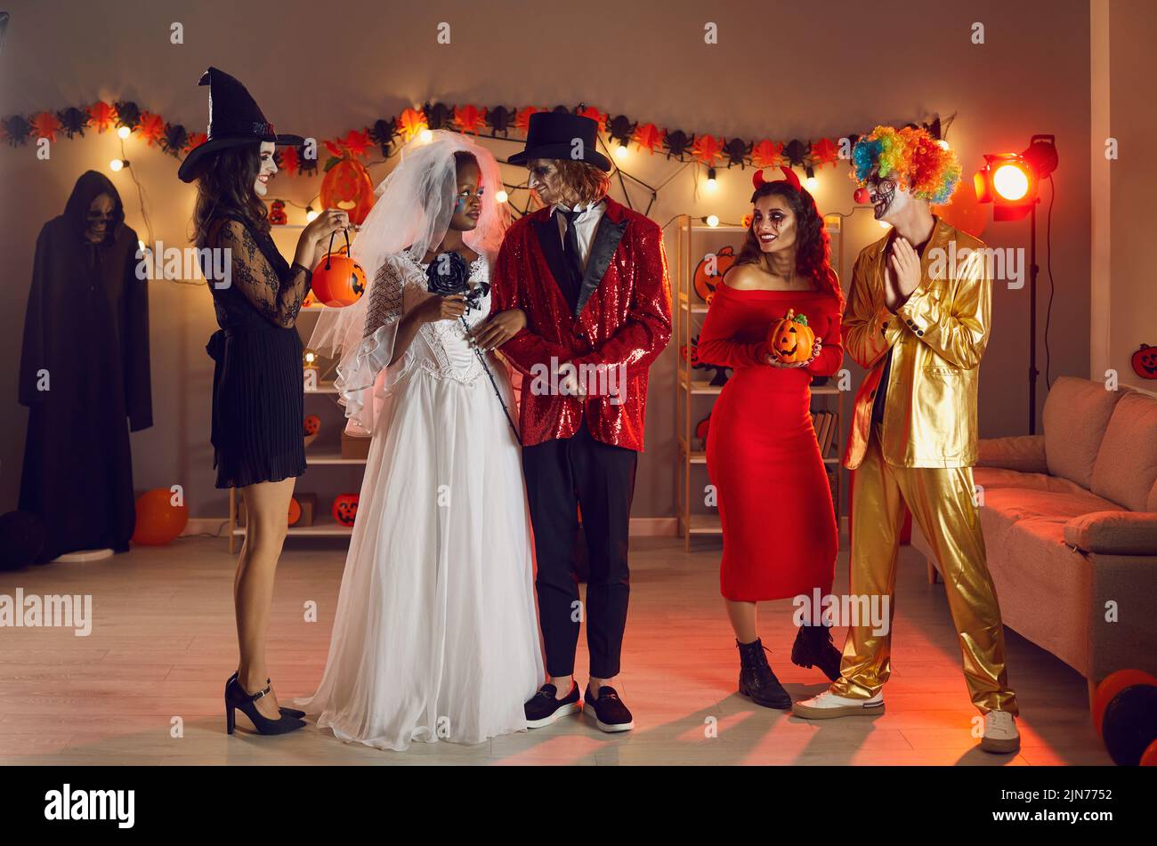 Mann und Frau in der Liebe gekleidet als tote Hochzeitspaar auf Halloween-Party mit Freunden Stockfoto