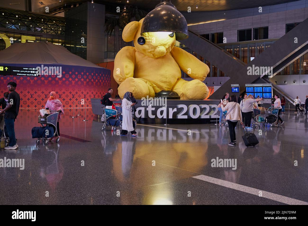 Abflughalle im Hamad International Airport, Doha, Katar bei Nacht mit der großen Lamp Bear Statue des Schweizer Künstlers Urs Fischer und # Qatar 2022 Stockfoto