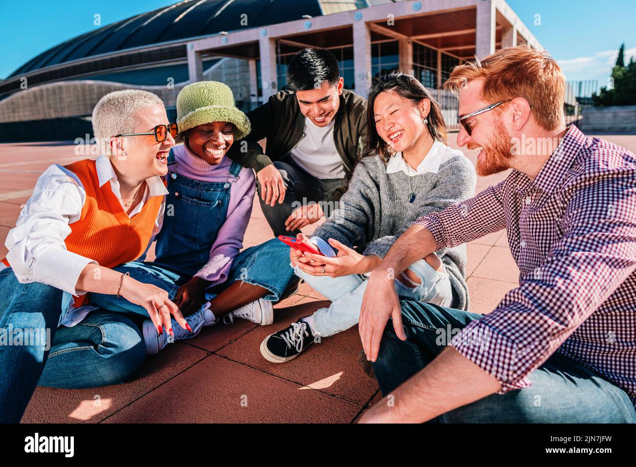 Junge Gruppenfreunde treffen sich, sitzen zusammen, haben Spaß und lächeln. Stockfoto